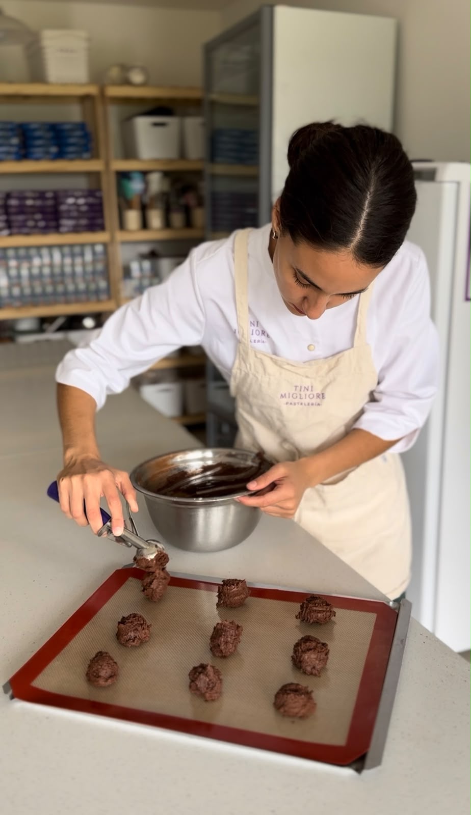 Tini trabajando con uniforme y delantal en su taller de pastelería